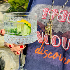 Vintage Gold Retractable Pencil Pendant photographed hanging on a necklace. Model is wearing a retro 80s top and drinking a G&T from a crystal glass