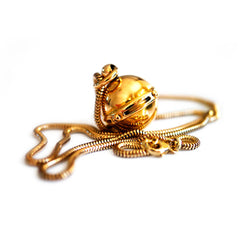 Antique Articulated Gold Gimbal Orb Compass Pendant on a gold chain photographed on a white background