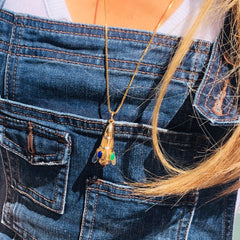 Bejewelled vintage Rocket Necklace worn on a gold chain around models neck. Model is wearing a light top with denim dungarees