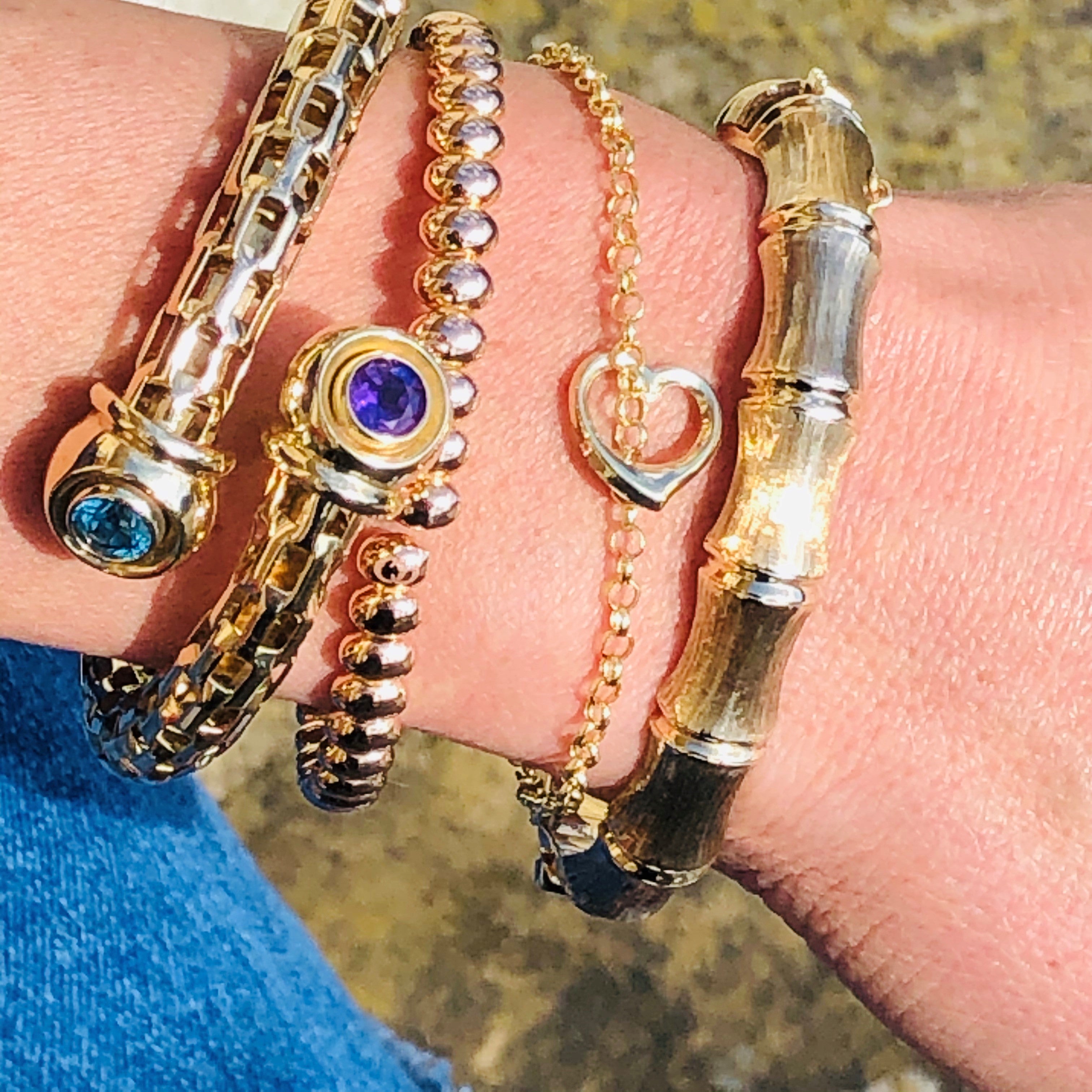 Alluring Amethyst & Topaz Torque Bangle photographed with other bangles on a models wrist